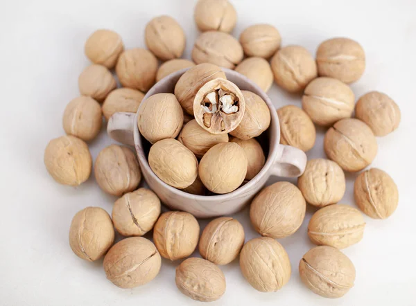 A lot of whole walnuts in a cup on a white background. Healthy food