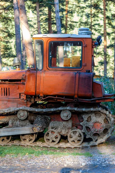 Un viejo tractor oxidado se encuentra cerca del granero en la hierba verde durante — Foto de Stock