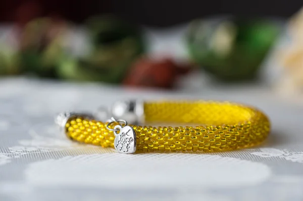 Crochet beaded bracelet from beads of yellow color on textile background