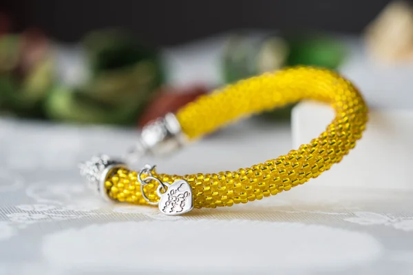 Crochet beaded bracelet from beads of yellow color on textile background