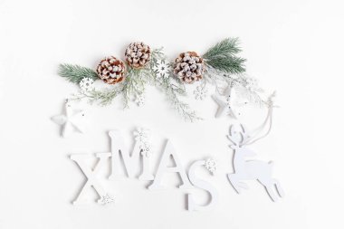 Beyaz harflerden, ağaç dallarından, çam kozalaklarından, geyiklerden, kar tanelerinden ve beyaz arka planda yıldızlardan oluşan yeniden kullanılabilir Noel dekoru içeren Xmas şenlik kompozisyonu. Sürdürülebilir Noel. Üst manzara, düz uzanma.