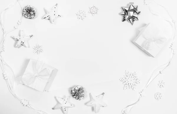 Beyaz ve gümüşten yapılmış çerçeveler: yıldızlar, DIY hediye kutuları, çam kozalakları, kar taneleri, beyaz kurdeleler. Noel modern İskandinav bestesi. Üst manzara, düz yatış. Metnin için boşluk kopyala.
