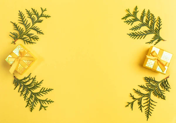 Xmas cartão com moldura de caixas de presente e ramos arborvitae verdes dispostos em amarelo com espaço de cópia no centro. — Fotografia de Stock