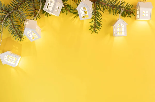 Yeşil köknar dalları çerçeveli Xmas sarı arkaplan ve kopyalama alanı ile parlak sarı Xmas ışıkları.