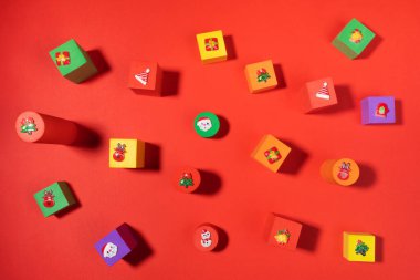 Üst görünüm yumuşak oyuncaklar. Kırmızı arka planda üzerinde Xmas sembolleri olan çok renkli çocuk küpleri..