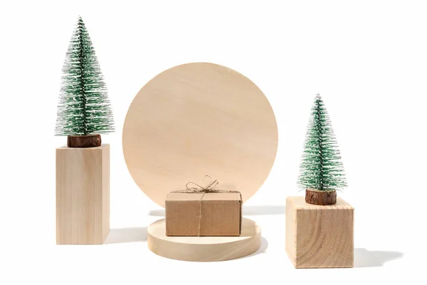 Composición navideña con árboles de Navidad decorativos y caja de cartón de regalo DIY en podios de madera en blanco con espacio para copiar. — Foto de Stock