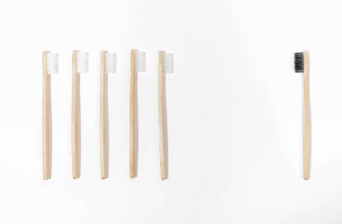 Beyaz eko dostu doğal bambu diş fırçalarına karşı beyaz zemin üzerinde siyah bir sıra.