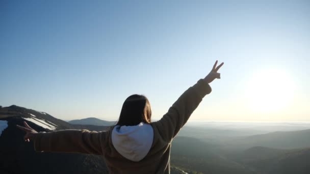 Une fille aux cheveux foncés rencontre joyeusement l'aube le matin dans les montagnes — Video