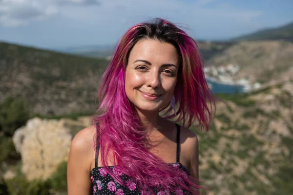 Hoş bir gülüşü ve sıcak havalarda pembe saçları olan bir kızın portresi.