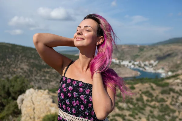 Sıra dışı görünüşlü, siyah saçlı, güneşe gülümseyen ve eğlenen bir kız.