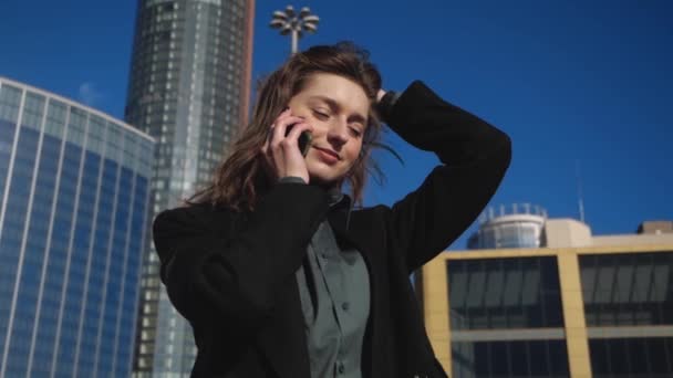 Business lady sets up meeting over the phone looking at clocks amid high-rises — Stock Video