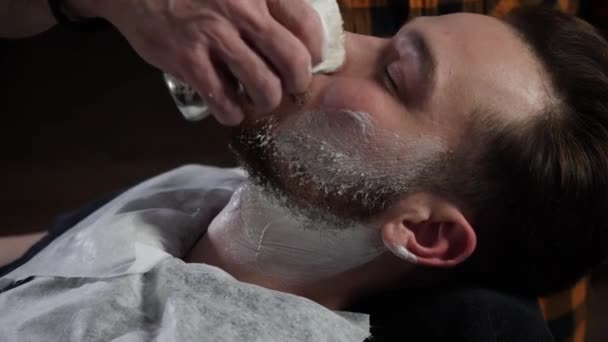 Barber fonctionne avec brosse à raser Mousse blanche sur le visage des clients — Video