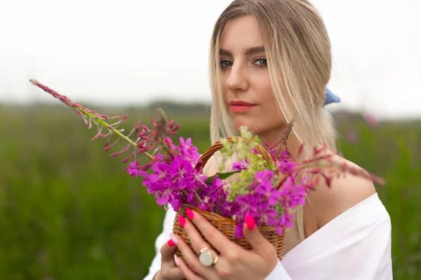Vrouw met natuurlijke make-up, met een boeket bloemen tegen het groene veld — Stockfoto