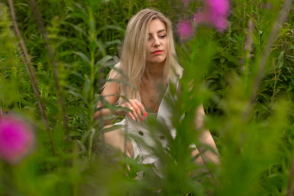 Sensuele jonge vrouw, zittend op het gras in een veld — Stockfoto