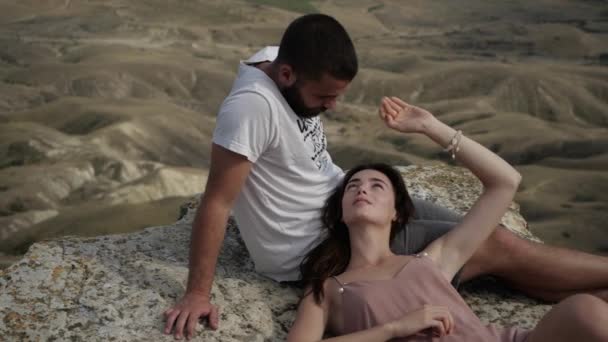 Jong paar ligt op de rand van een klif meisje in liefde kijken naar een jongen — Stockvideo