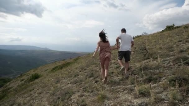 Jong stel loopt door de vallei te midden van bergen en wolken — Stockvideo