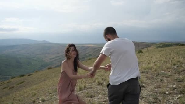 La feliz pareja cogida de la mano, corriendo por una llanura bajo el cielo nublado — Vídeo de stock