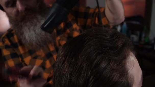 Cabeleireiro adulto seca a cabeça dos clientes com secador de cabelo na barbearia — Vídeo de Stock