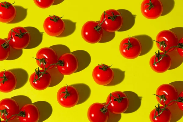 Vibrant red tomatoes pattern on a yellow trendy background. Flat lay concept.