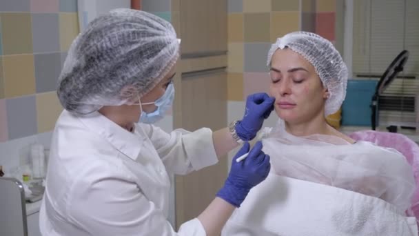 Косметик готовит косметическую процедуру для молодой женщины — стоковое видео
