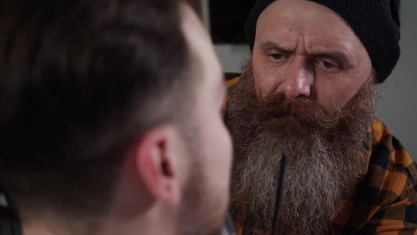 Adulto barbeiro masculino com uma longa barba corta a barba de um jovem — Vídeo de Stock