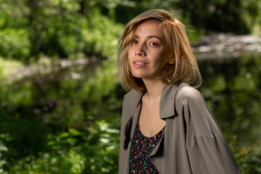 Gri ceketli güzel sarışın bir kız kameraya bakar.