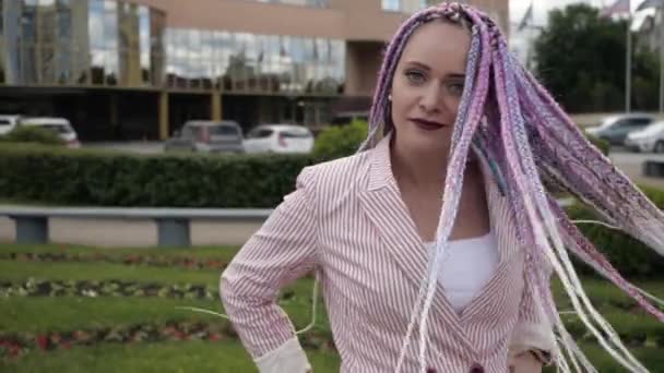 Mladá kreativní žena s pestrobarevnými dlouhými copánky se podívá do kamery — Stock video