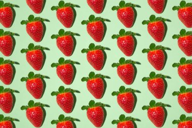 Tertemiz yeşil arka planda bir sürü kırmızı olgun çilek