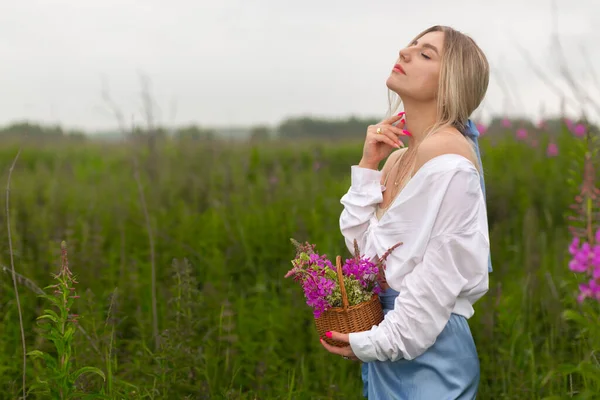 Sensueel mooi meisje in een wit shirt staat in het veld houden — Stockfoto