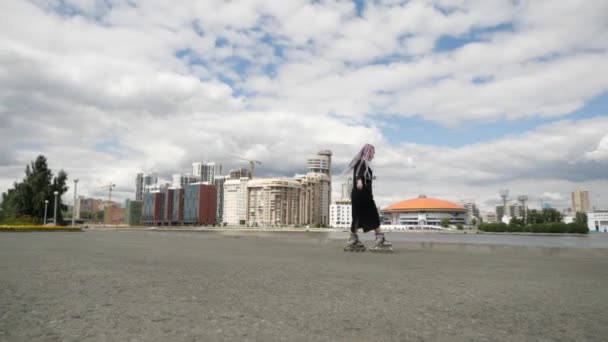 A young girl with colored long pigtails and a long dress does tricks skating — Stock Video