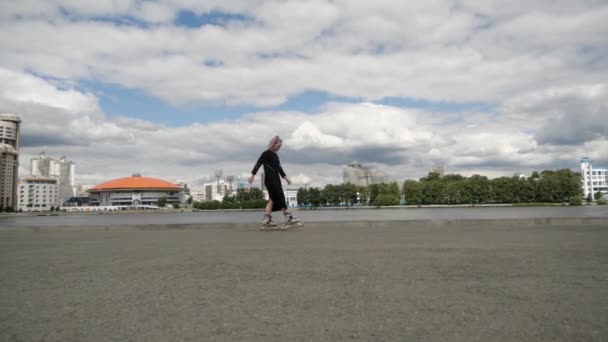 Interessante ragazza con trecce colorate rotola sull'asfalto sui pattini a rotelle — Video Stock