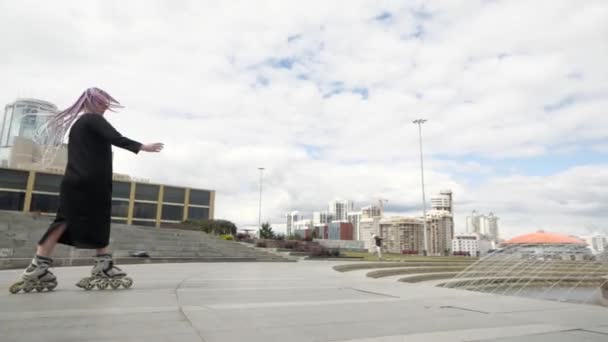 En intressant flicka utför tricks på rullskridskor nära stadens fontän — Stockvideo