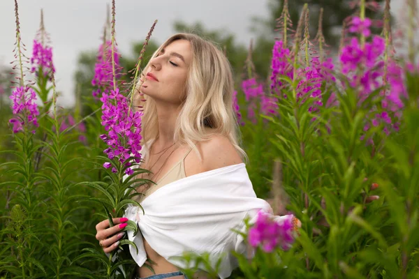 Sexy vrouw staat met haar ogen dicht in het midden van het veld met bloemen — Stockfoto