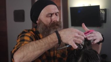 Yetişkin erkek kuaför kuaförde erkek bir müşteriye saç teli kesiyor.