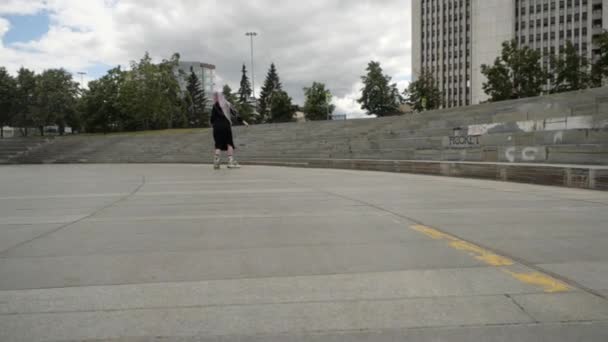 A girl in a long black dress rides her back forward on roller skates — Stock Video