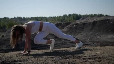 Beyaz spor üniformalı genç bir kadın ayakları için spor egzersizleri yapıyor.