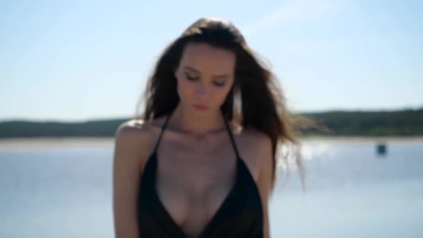 Молодая сексуальная девушка в черном купальнике чувственно смотрит прямо в камеру — стоковое видео