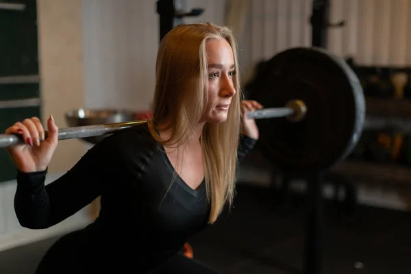 Güçlü bir atletik kız sırtında halterle çömelme egzersizi yapar.
