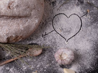 Sevgililer günü için ev yapımı yemekler. Ev yapımı ekmeğin yanında beyaz un üzerinde kalp. 