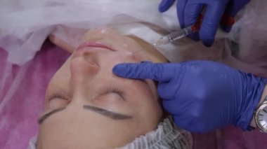Doktor yakın plan güzellik uzmanı kız hastaya hiyalüronik asit enjekte ediyor.