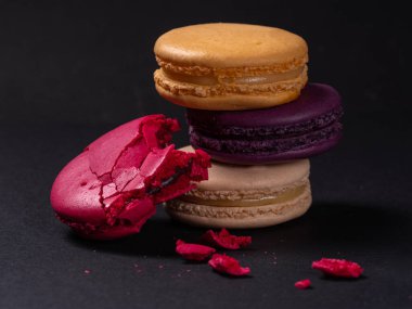 Siyah arkaplanlı Fransız renkli badem kurabiyeleri.