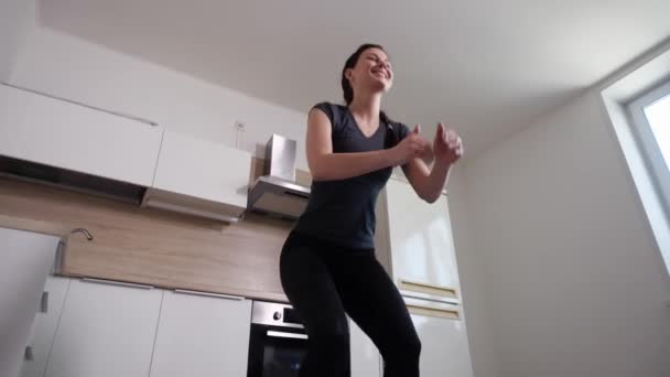 Dziewczyna wykonuje przysiady ćwiczeń na tle białej kuchni — Wideo stockowe