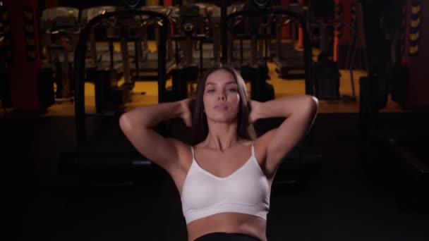 Chica atractiva con una hermosa figura realiza un ejercicio de abdominales en el gimnasio — Vídeos de Stock