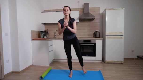 Esmer bir kız mutfakta ayaklarını sallama egzersizi yapıyor. — Stok video