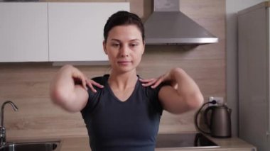 Genç, tatlı bir kız evde egzersiz yapıyor mutfakta duruyor.