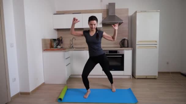 Esmer bir kız egzersiz yapıyor mavi renkli bir jimnastik minderinde zıplayarak. — Stok video