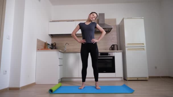 Chica morena delgada se para en la alfombra azul de la casa en la cocina — Vídeo de stock