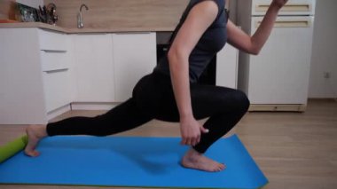 Esmer kız, evde bir hamleyle çömelme egzersizi yapıyor. 