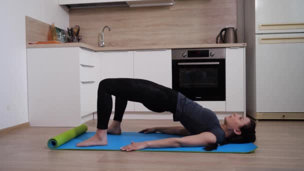 体操マットの上に横たわる足の筋肉を強化するための女の子の運動 — ストック動画