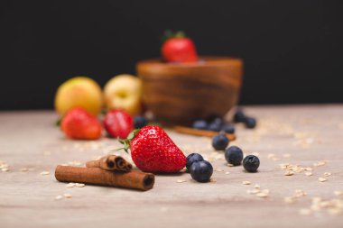 Lezzetli meyveler ve tahıllar ahşap bir kasede yulaf lapasının arka planında.